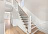 Light and Bright entryway and stairs to second floor Hardwood flooring, wainscoting, solid panel doors, wood-finish stair treads, and wrought iron bal