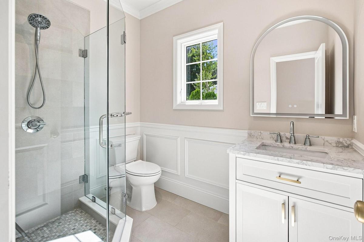 First Floor full bath - glass-enclosed shower with pebble-tile flooring and chrome fixtures