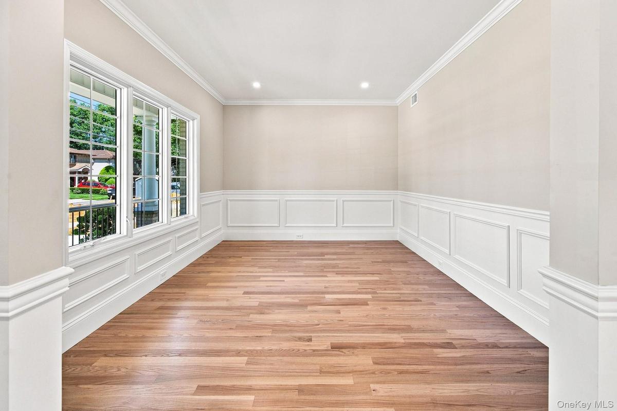 Flexible space: office, study, den, playroom. Wood-finish flooring, white paneled wainscoting, crown molding, recessed lighting, and multiple windows 