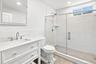 Lower level bath with white vanity with an integrated rectangular sink, chrome fixtures, and white countertop.