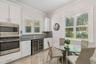 A bright kitchen corner featuring double ovens and a wine refrigerator
