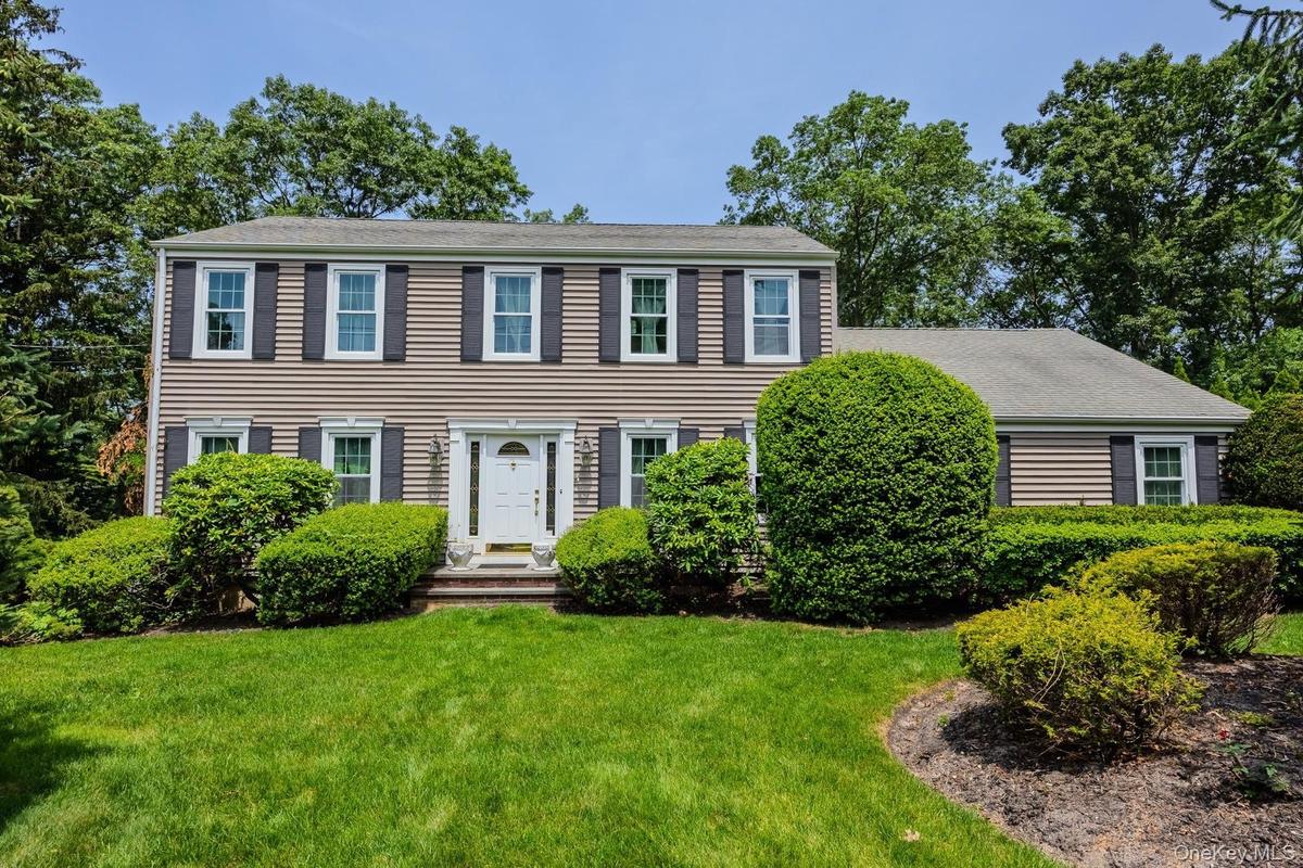 Traditional exterior with beige siding, dark shutters, a white front door, and a well-maintained lawn