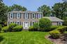 Traditional exterior with beige siding, dark shutters, a white front door, and a well-maintained lawn