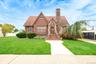 Brick exterior with stone accents, steeply pitched roof, and an arched entry