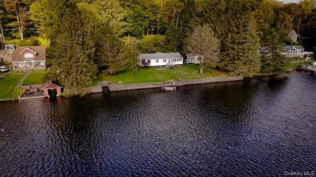Waterfront property with a stone retaining wall, mature trees, and a detached boathouse
