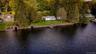 Waterfront property with a stone retaining wall, mature trees, and a detached boathouse