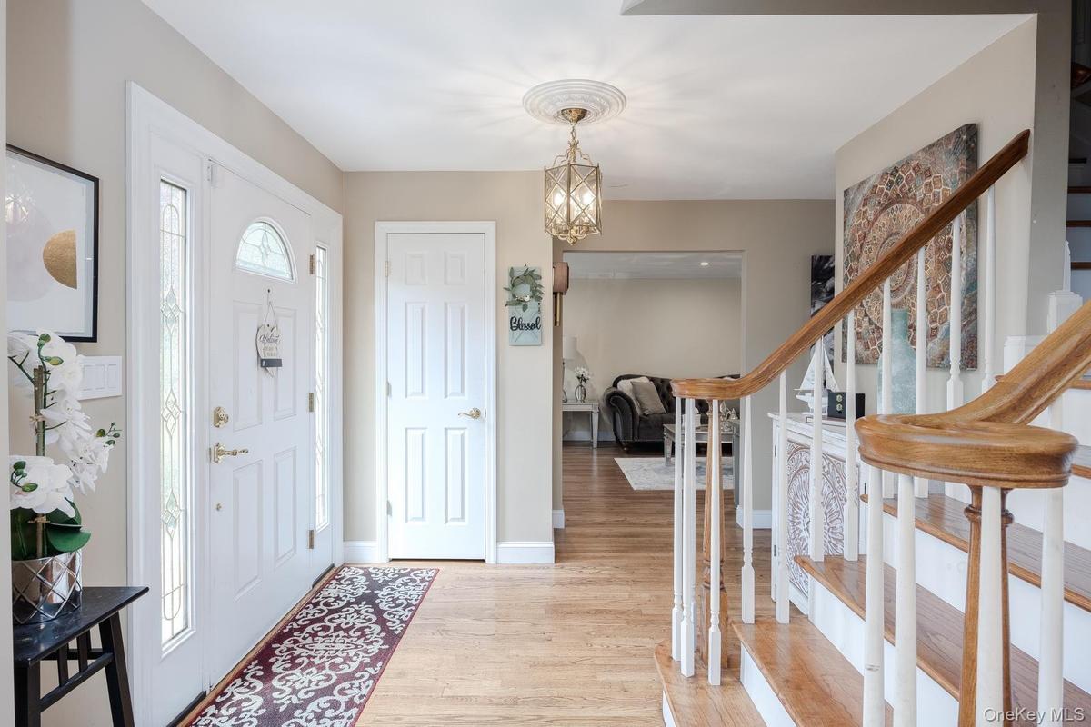 Entryway featuring wood-finish flooring, a white paneled entry door with sidelights, a decorative ceiling medallion with an attached light fixture, an