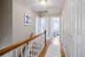 Hardwood flooring throughout the hallway and staircase, featuring white risers and a wood-finish handrail