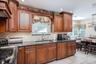 Rich wood cabinetry with decorative molding, dark stone countertops, diamond-patterned tile backsplash, and a contemporary sink faucet
