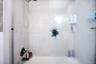 Tub-shower combination featuring white tile surround with  brushed nickel fixtures