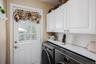 laundry room with white paneled door with window, overhead white cabinetry, and built-in countertop