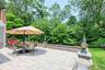 Expansive paver patio with a stone retaining wall and lush perimeter landscaping