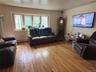 Hardwood flooring throughout, bay window with wood trim, and wall-mounted television