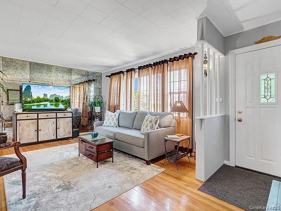 Hardwood flooring throughout, mirrored accent wall, white paneled entry door with decorative glass insert, and a partial room divider