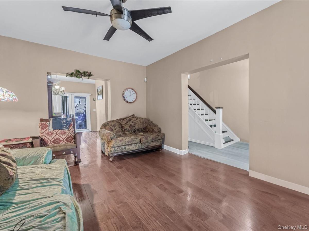 Living room with wood finished floors, stairs, and ceiling fan