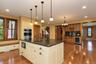 Kitchen island with dark countertop and white cabinetry, integrated microwave, and undermount sink