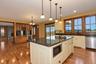 Kitchen island with dark countertop and white cabinetry, integrated microwave, and undermount sink