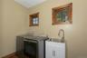 Laundry area featuring wood-framed windows, a utility sink with a gooseneck faucet, and white base cabinetry