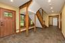 Foyer featuring tile flooring, a solid wood entry door with glass panels, wood-framed windows, a wood staircase, and recessed lighting