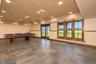 Expansive room featuring multi-toned tile flooring, recessed ceiling lighting, a wood-framed triple window, and wood-framed French doors