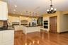 Kitchen featuring hardwood flooring, cream-finish cabinetry, dark countertops, a central island, and recessed lighting