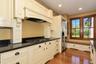 Cream-painted cabinetry, dark countertops, built-in window seating, stainless steel refrigerator, and wood-finish flooring