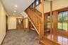 Two-story entry with natural wood staircase, wood-framed windows, recessed lighting, and patterned floor tile