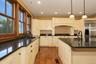 Cream-colored cabinetry with dark hardware, dark countertops, wood-finish flooring, and recessed ceiling lighting