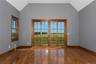 Vaulted ceiling, wood-finish flooring, full-light French doors with wood trim, wood-trimmed window, and balcony with black railing