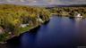 Waterfront property featuring a private dock, expansive lawn, and mature trees, set against a forested hillside