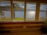 Expansive windows offering water frontage, wood-paneled interior walls, and a wood-finish floor