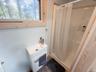Compact bathroom featuring a white vanity with integrated sink, chrome faucet, and a stand-up shower with a white enclosure