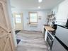 Wood-finish flooring throughout, stainless steel gas range, wooden open shelving, light wood countertops, and a full-light panel door