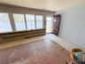 Multiple large windows, wood plank wainscoting, light blue painted walls, and a substantial wooden entry door