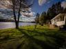 Lakefront property with a white exterior, a wood-finish deck, and mature trees