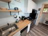 Kitchen featuring wood-finish countertops, stainless steel sink, white cabinetry, stainless steel dishwasher, and a gas range