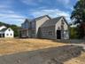 Newly constructed residence featuring gray siding and a dark shingle roof