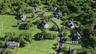 Residential development featuring multiple properties, expansive green spaces, paved roadways, and mature tree coverage