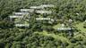 Aerial perspective of a development featuring multiple available lots, established residences, private driveways, and expansive green spaces surrounde