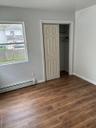 Unfurnished bedroom featuring a baseboard heating unit, dark wood-style floors, and a closet