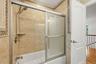 Hallway bathroom, marble tile, Anderson window, recessed lighting.