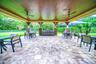 Expansive covered patio featuring a wood-finish ceiling, paver flooring, stone-clad columns, built-in grill station, and integrated ceiling fans