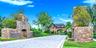 Paver driveway flanked by stone entryway pillars and lush landscaping