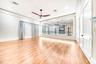 Spacious room featuring wood-finish flooring, a full mirrored wall, and a ceiling fan