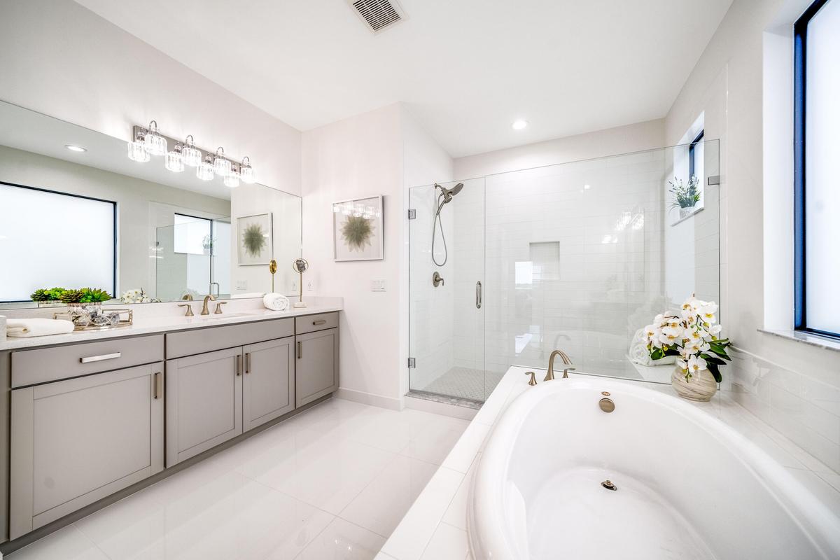 Dual vanity with undermount sinks, a built-in soaking tub, a glass-enclosed shower, and large format floor tiling