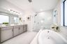 Dual vanity with undermount sinks, a built-in soaking tub, a glass-enclosed shower, and large format floor tiling