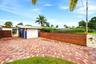 Herringbone brick paver driveway with a wood-slat fence and mature landscaping