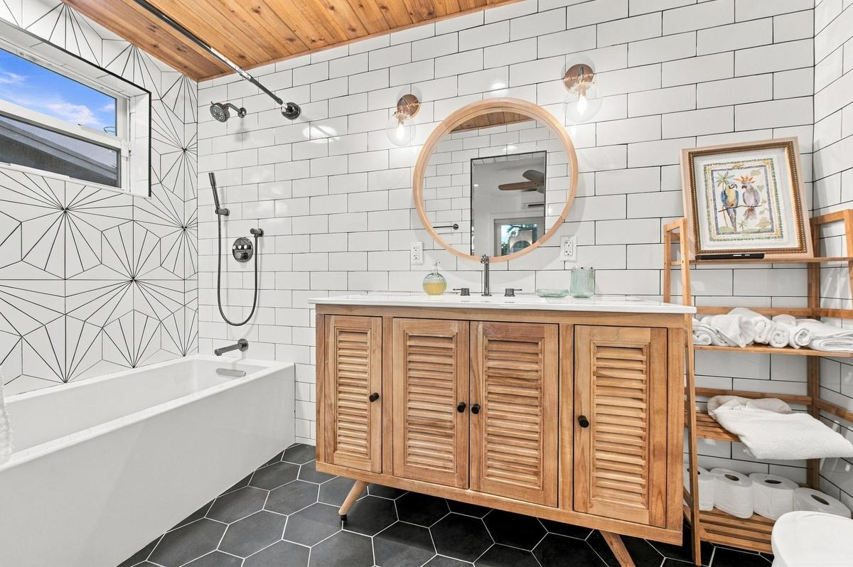 Wood-finish ceiling, white subway tile walls, geometric pattern shower wall tile, deep soaking tub, and hexagon floor tiling