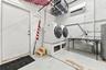 White front-loading washer and dryer, exposed concrete block walls, and overhead shelving