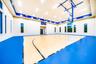 Indoor court with a polished wood-finish playing surface, blue-finished perimeter, and high ceilings